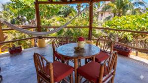a table and chairs on a porch with palm trees at Troncones Point Hostel in Troncones +92 photos