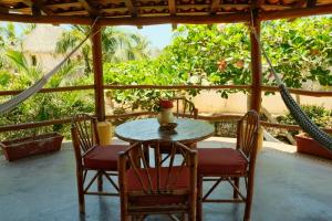 a table with chairs and a vase on a porch at Troncones Point Hostel in Troncones
