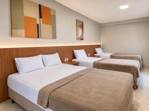 two beds in a hotel room with paintings on the wall at Exclusive Hotel in Campos Sales