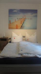 ein Bett mit Kissen und ein Gemälde eines Piers in der Unterkunft FeWo Strohbach in Meißen