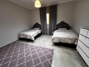 a bedroom with two beds and a rug on the floor at شقة مخدومة 101 in Medina