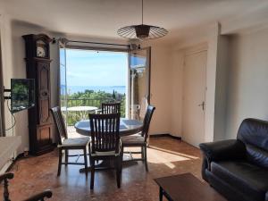a living room with a table and chairs and a clock at Les messugues aux issambres in La Garonnette-Plage +18 photos
