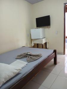 a bedroom with a bed with a television and a desk at Hotel Dunil in Araguaína