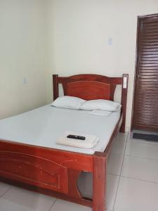 a bed with a wooden frame with a remote control on it at Hotel Dunil in Araguaína