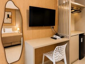 a room with a mirror and a desk with a tv at Exclusive Hotel in Campos Sales