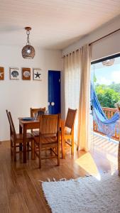 a dining room with a table and chairs and a window at Recanto Manoah MAR in Caraíva