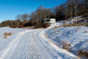 Eine schneebedeckte Straße mit einem Wohnmobil am Straßenrand in der Unterkunft Forest Capsule in Uddevalla