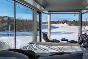 ein Zimmer mit Blick auf ein schneebedecktes Feld durch Fenster in der Unterkunft Forest Capsule in Uddevalla