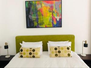 a bed with two pillows and a painting on the wall at The Tarragon in Hout Bay +56 photos
