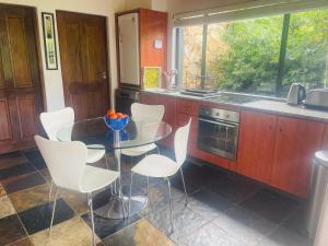 a kitchen with a glass table and white chairs at The Tarragon in Hout Bay