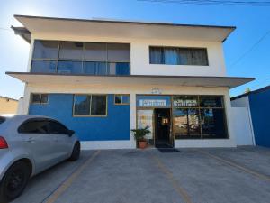 a white car parked in front of a blue building at Hotel Pensión Galicia in Obaldía