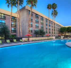 a swimming pool in front of a hotel with palm trees at DoubleTree by Hilton Phoenix North in Phoenix