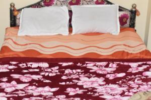 a bed with a floral bedspread and two pillows at JAJABAR Homestay in Dum Duma