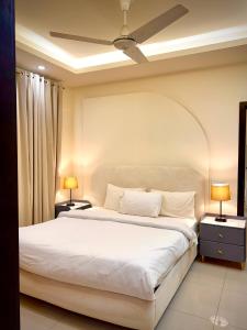 ein Schlafzimmer mit einem großen weißen Bett und zwei Lampen in der Unterkunft Executive Penta Studio Luxury Apartments DHA Lahore in Lahore
