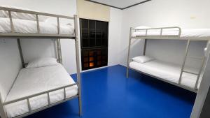 two bunk beds in a room with a blue floor at First Avenue Male Hostel BSB in Bandar Seri Begawan