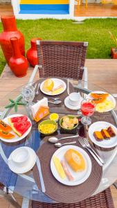 a glass table with plates of food on it at Recanto Manoah MAR in Caraíva +16 photos