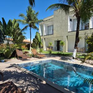 a swimming pool in front of a building with palm trees at Pousada Sky Dream Beach Mutá Frente Mar By LVF in Porto Seguro