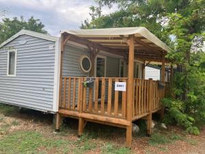 a house with a deck with awning on it at Camping Mas Sud Ardèche in Saint-Just +15 photos