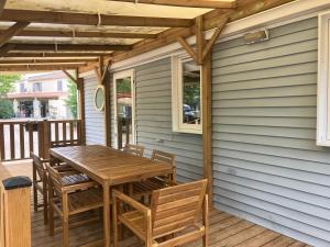 a deck with a wooden table and chairs on a house at Camping Mas Sud Ardèche in Saint-Just