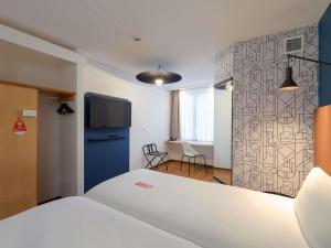 a bedroom with a white bed and a tv on a wall at ibis Nürnberg Hauptbahnhof in Nuremberg