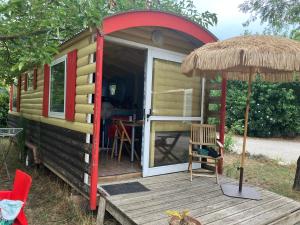 a tiny house with a porch and an open door at Camping Mas Sud Ardèche in Saint-Just