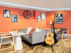 a living room with a couch and a guitar at Novotel Paris Rueil Malmaison in Rueil-Malmaison