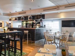 a restaurant with tables and chairs and a bar at Novotel Paris Rueil Malmaison in Rueil-Malmaison