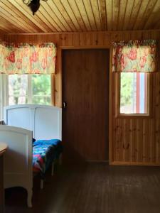 a bedroom with a bed and two windows with curtains at Lomakoti Tuulensuoja in Kärväsjärvi