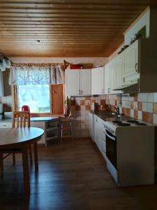 a kitchen with white cabinets and a table and a sink at Lomakoti Tuulensuoja in Kärväsjärvi