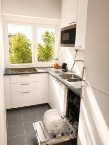 a white kitchen with a dishwasher and a sink at Antwerp Hideaway, outside of low emission zone in Antwerp