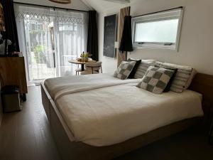 a bedroom with a large bed with a window and a table at Style Gardenhouse Zwanenburg near AMSTERDAM, HAARLEM, ZANDVOORT in Zwanenburg