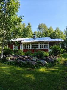 a red house with a solar roof on a yard at Lomakoti Tuulensuoja in Kärväsjärvi