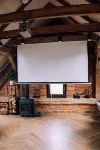 a large white screen in a room with a fireplace at Stodoła Baryczy in Postolin