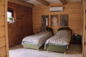 two beds in a room with wooden walls at Stodoła Baryczy in Postolin