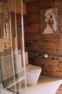 a bathroom with a toilet and a brick wall at Stodoła Baryczy in Postolin +24 photos