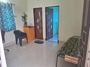 a room with a chair a table and a door at Aadyasha in Pānchagān