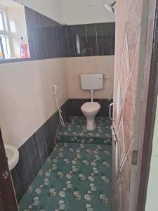 a bathroom with a toilet and a green tile floor at Aadyasha in Pānchagān