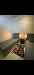 a bedroom with two beds and a rug on the floor at Benjelloun in Marrakesh