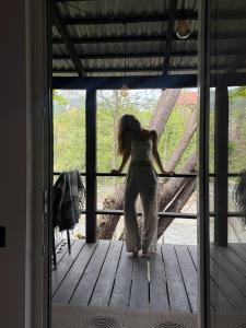 a woman standing on a porch looking out the window at Molfar green  +7 photos