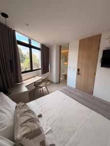 a bedroom with a large white bed and a desk at Hotel Palmaris Urban Villeta in Villeta