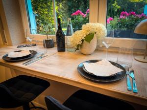 ein Tisch mit Tellern und Gläsern und einer Vase mit Blumen in der Unterkunft SaaleLoft in Hirschberg