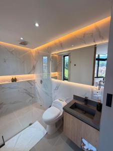 a white bathroom with a toilet and a sink at Hotel Palmaris Urban Villeta in Villeta