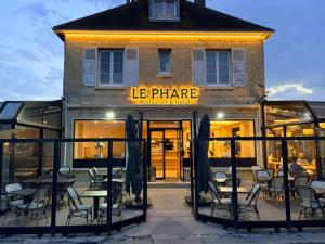 a restaurant with tables and chairs in front of a building at Hôtel Le Phare in Ouistreham