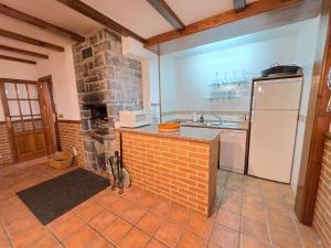a kitchen with a brick fireplace and a white refrigerator at El balcón de Cotefablo Chalet de Montaña con Jardín y Vistas - Arafita Apartamentos in Gavín +28 photos