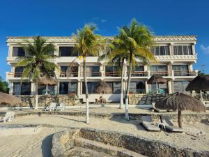 a hotel on the beach with palm trees and chairs at Condumel in Cozumel