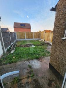 a backyard with a fence and a yard with grass at The Willow in Aveley