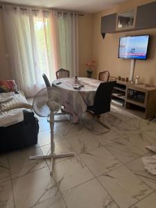 a living room with a table with chairs and a television at Chez Séverine in Avignon