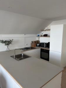 a white kitchen with a sink and a refrigerator at Central apartment for ONS in Stavanger