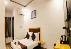 a hotel room with a bed and a desk at Hotel A P S Townhouse in Prayagraj