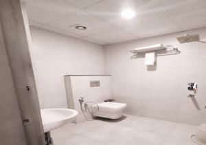 a white bathroom with a toilet and a sink at Hotel A P S Townhouse in Prayagraj